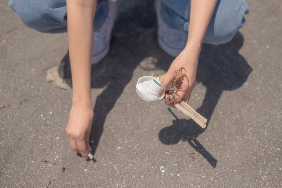 A person wearing a white t-shirt with the words 'NO PLANT B' printed in green, white gloves, and a black wristwatch is holding a clear plastic bag filled with face masks and disposable gloves. The ind
